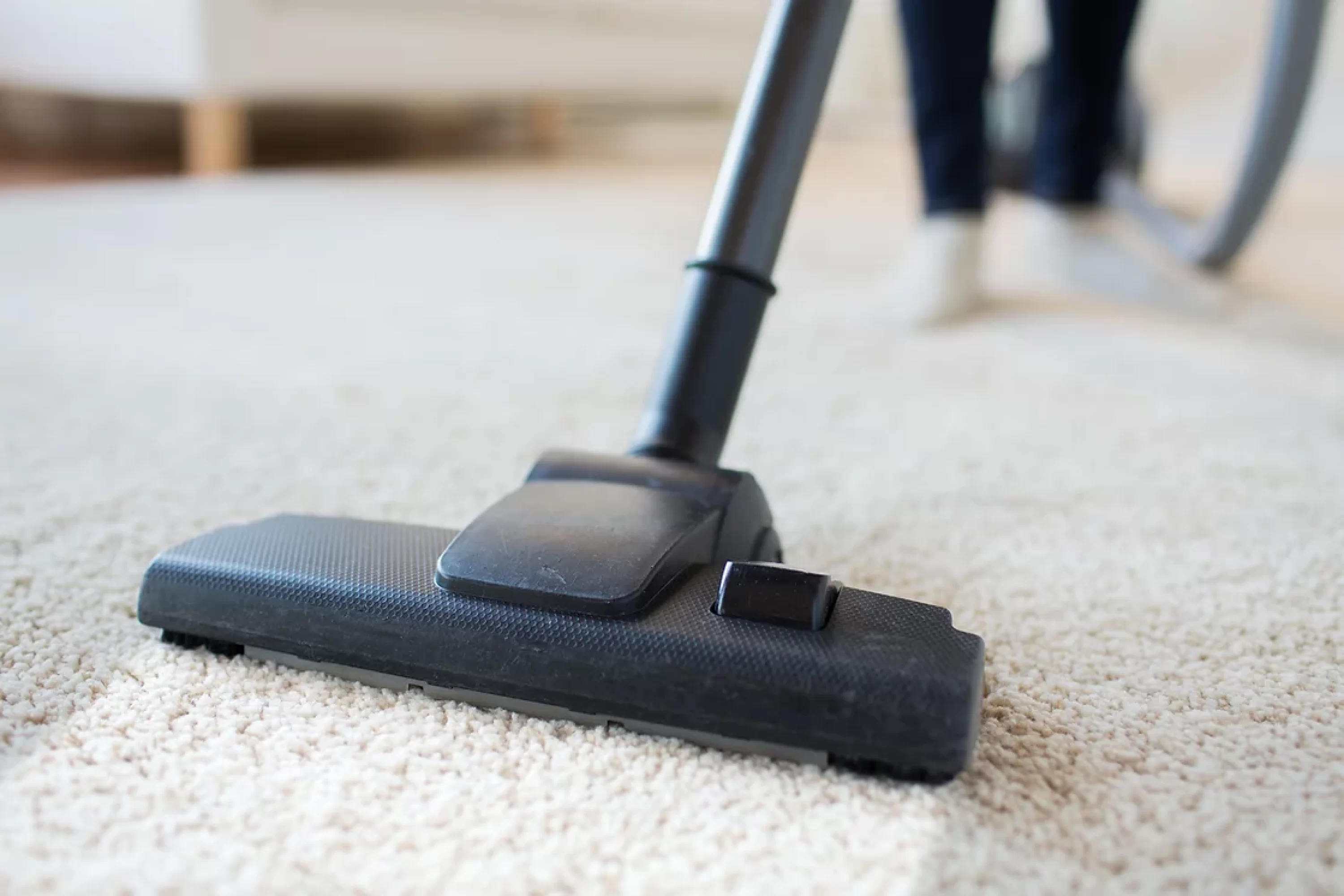A person using a vacuum cleaner to clean a carpet, demonstrating effective home maintenance and cleanliness.